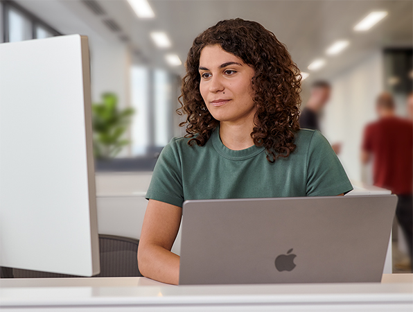 สมาชิกทีม Apple กำลังใช้ MacBook และ Studio Display อยู่ในสำนักงาน