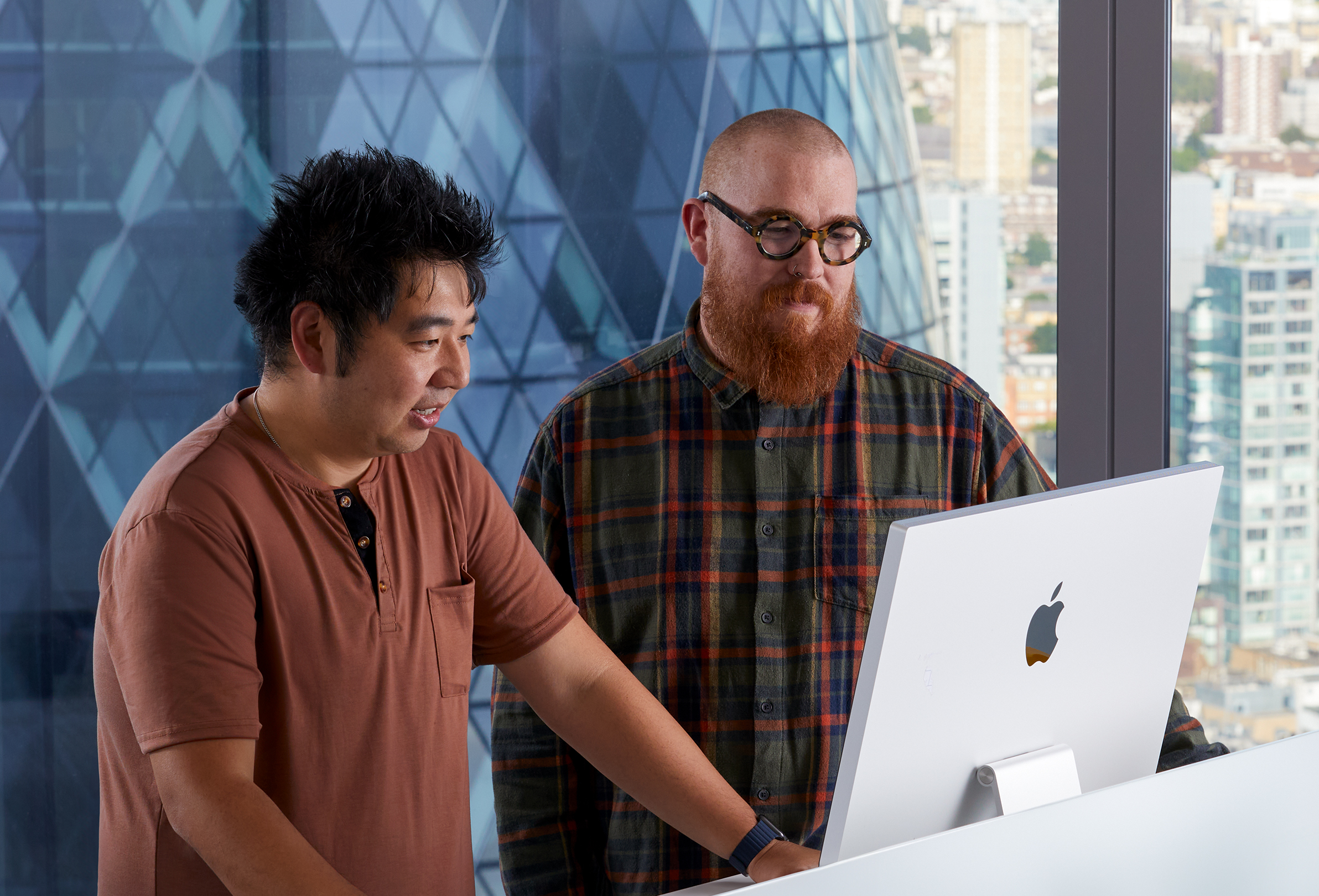 เพื่อนร่วมงาน Apple 2 คนกำลังทำงานร่วมกันขณะที่ใช้ iMac