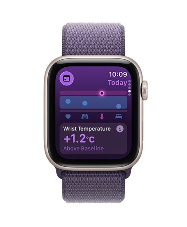 Apple Watch SE 3 z aluminiową kopertą w kolorze księżycowej poświaty i opaską sportową w kolorze mlecznego fioletu. Ekran pokazuje wskaźniki temperatury nadgarstka. Na prawym boku urządzenia pokrętło Digital Crown.