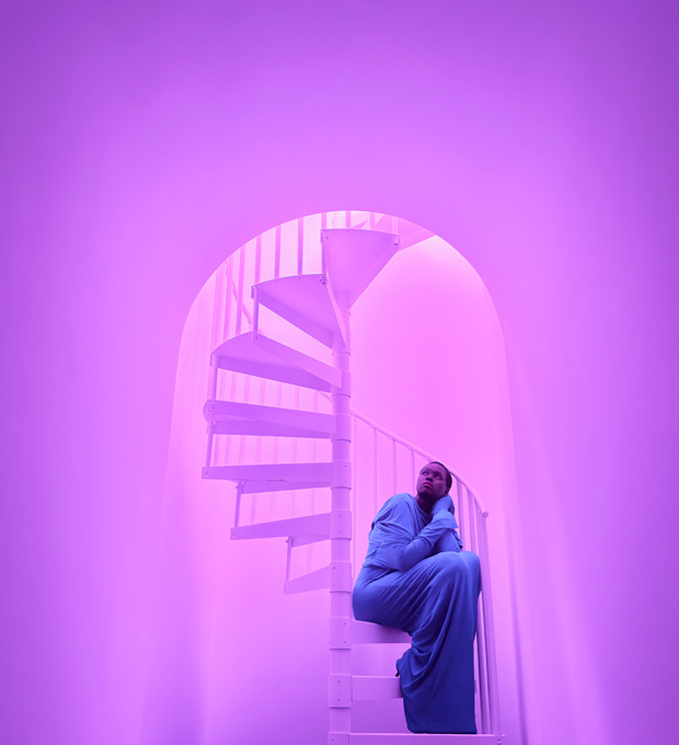Foto di una donna seduta su una scala a chiocciola, per mostrare le capacità fotografiche del sistema di fotocamere Pro quando c’è poca luce.