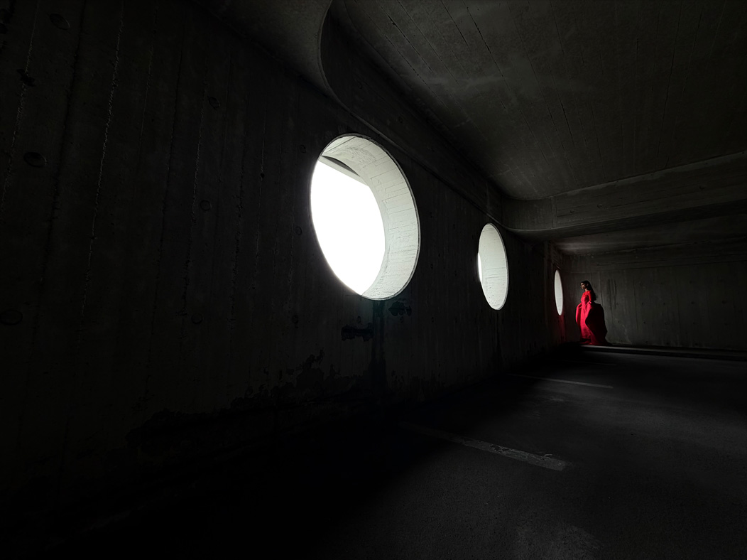 Una donna con un lungo vestito rosso fotografata in piedi in una stanza vuota. Nell’app Foto la lunghezza focale viene regolata a 13 mm, per mettere in evidenza le capacità del sistema di fotocamere Pro