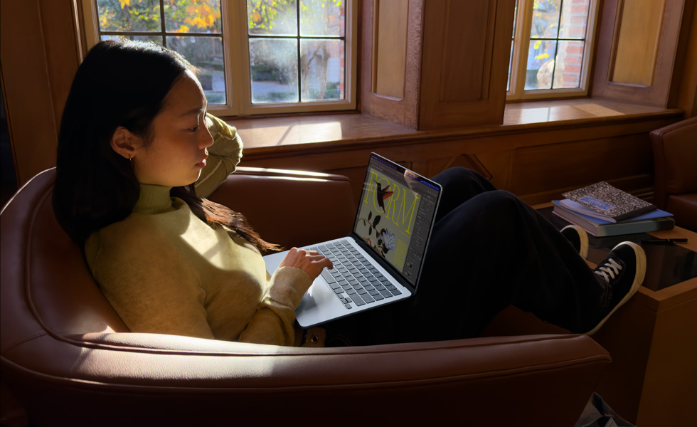 En person som sitter på en stol och använder sin MacBook Air